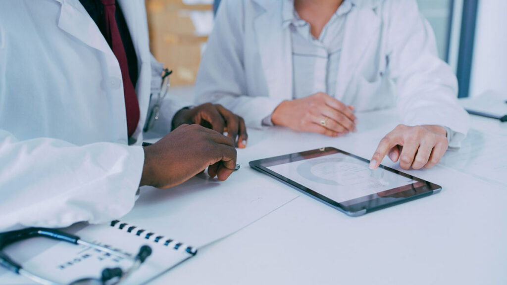 Two doctors review data on a tablet.
